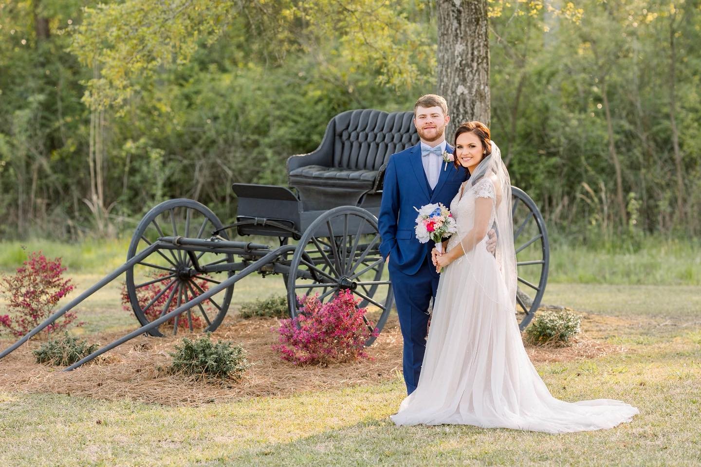Bride and groom on the grounds near a carriage.