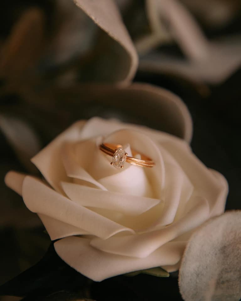 Wedding rings resting inside a white rose detail.