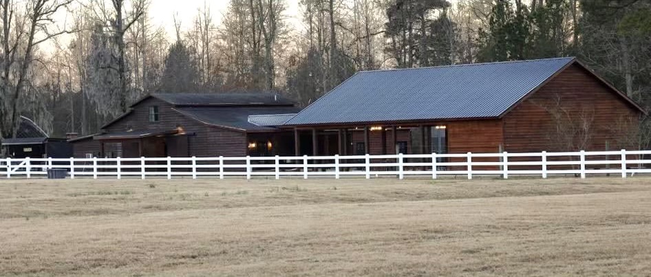 The Horse Barn farm exterior behind a white fence.